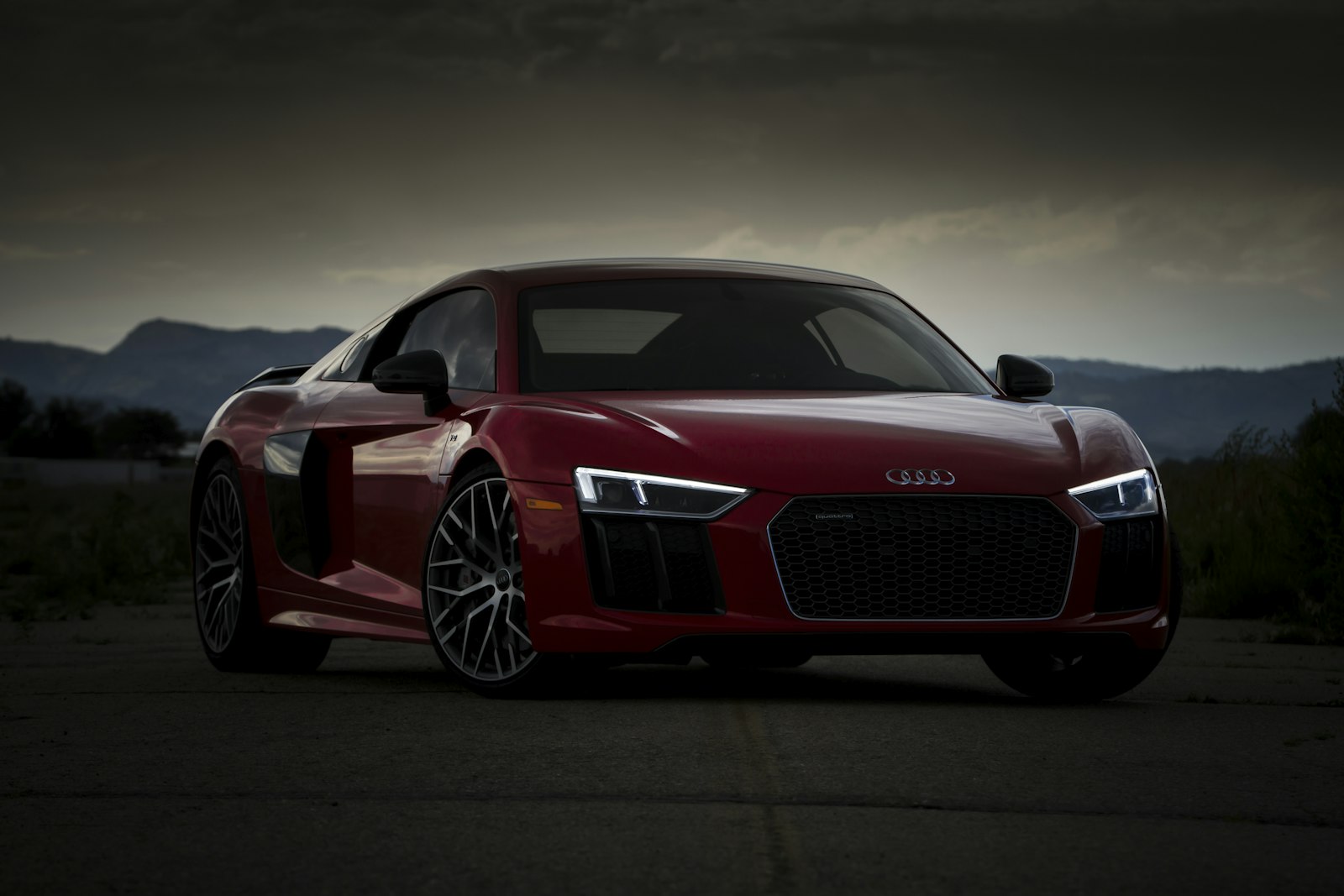 Audi R8 vermelho ao entardecer com montanhas ao fundo